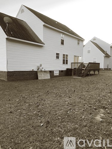 A white barn with a black roof and a wooden ramp leading to the door.