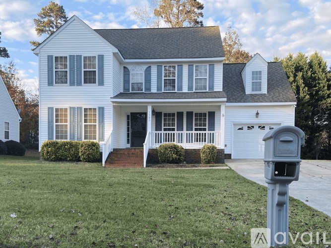 A white house with a grey roof and a mailbox in front.
