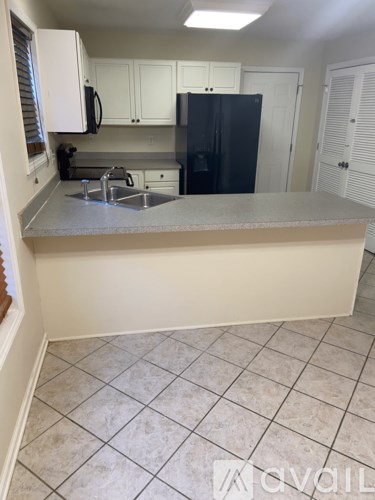 A kitchen with a black refrigerator and white cabinets.