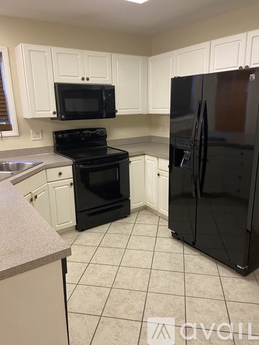A kitchen with black appliances and white cabinets.