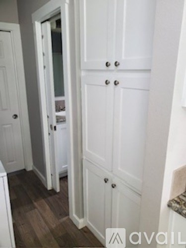 A white cabinet with a glass door is in a room.