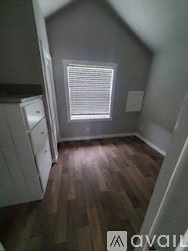 A room with wooden floors and a window with blinds.