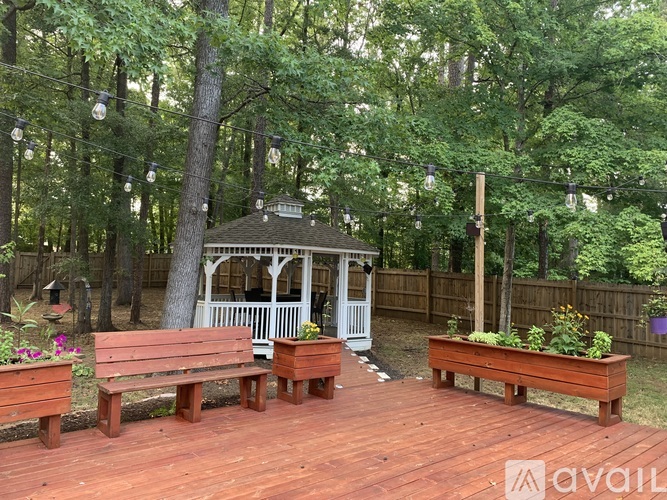 A gazebo is surrounded by benches and trees.