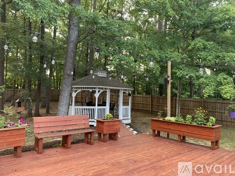 A gazebo is surrounded by benches and trees.