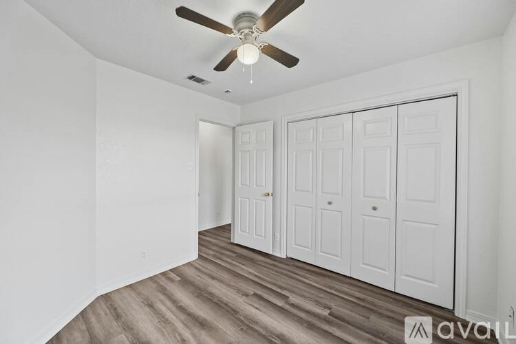 A room with a ceiling fan and three white doors.