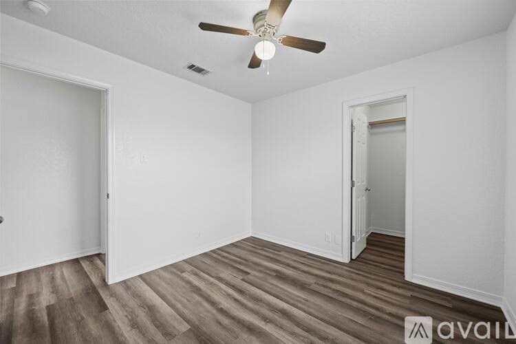 A room with a ceiling fan and wooden flooring.