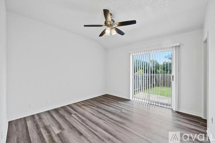 A room with a ceiling fan and sliding glass doors leading to a patio.