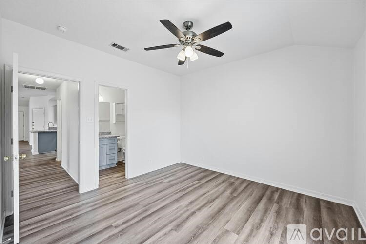 A room with a ceiling fan and wooden flooring.
