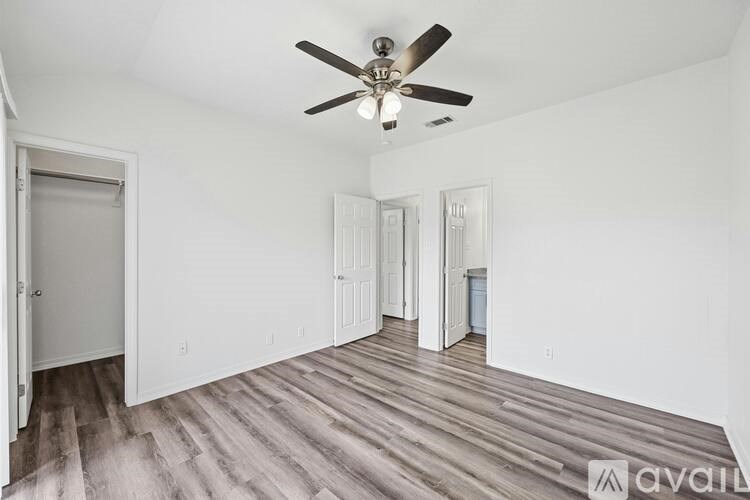 A room with a ceiling fan and wooden flooring.