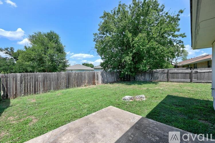A backyard with a wooden fence and a concrete patio.