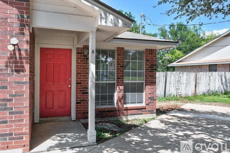 A red door is on the left side of a white porch.