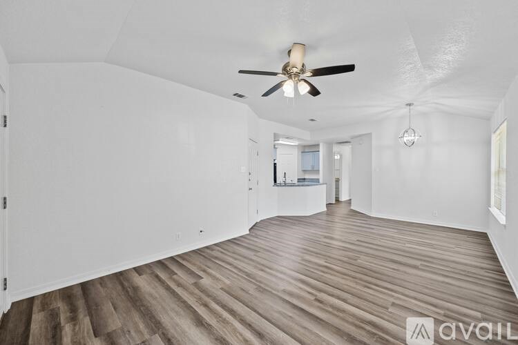 A room with a ceiling fan and wooden flooring.
