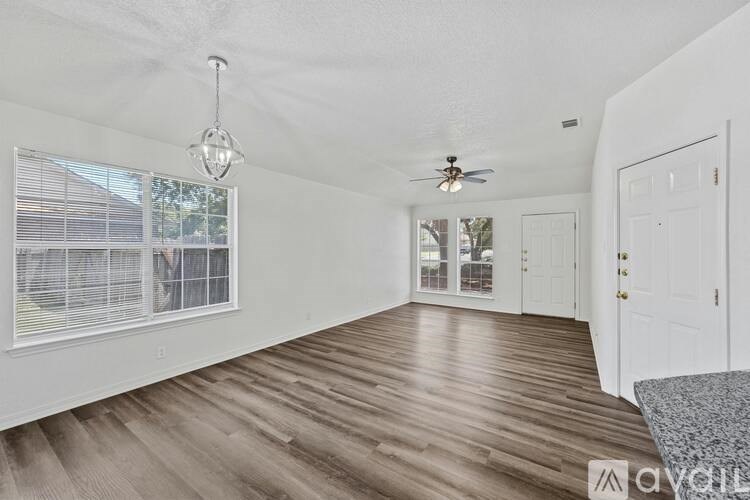 A room with wooden floors and white walls, a ceiling fan, and a window with blinds.