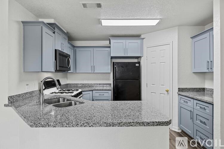 A kitchen with granite countertops and a black refrigerator.