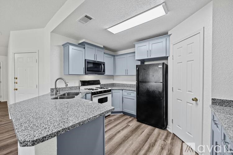 A kitchen with a black refrigerator and a granite countertop.