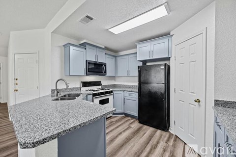 A kitchen with a black refrigerator and a granite countertop.