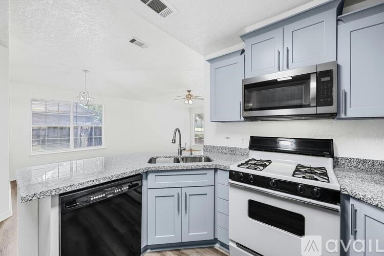 A kitchen with a black dishwasher, white oven, and a black stove top.