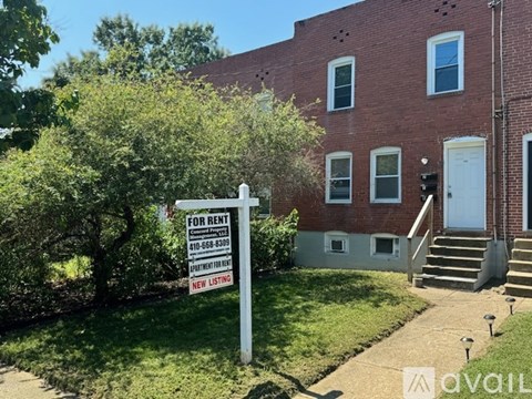 A red brick house with a for rent sign in front.