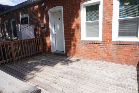 A white door is on the left side of a brick building.