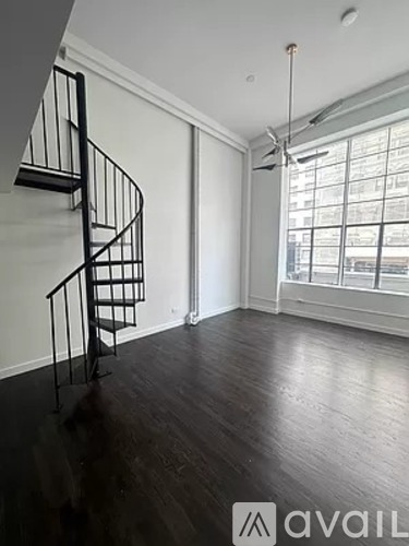 A room with a spiral staircase and a window.