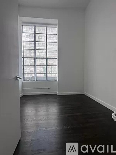 A room with a window and wooden flooring.