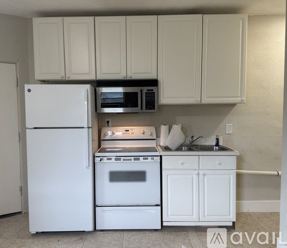 A white refrigerator and oven in a kitchen with white cabinets.