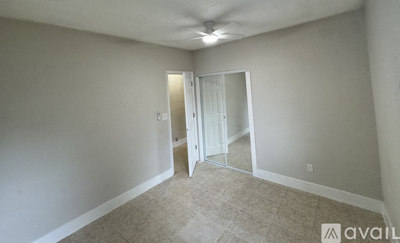 A room with a carpeted floor and a ceiling fan.