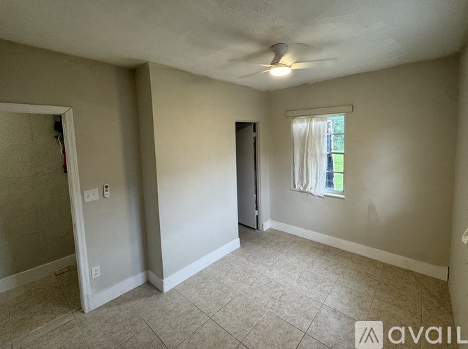 A room with a window and a door is available for rent.