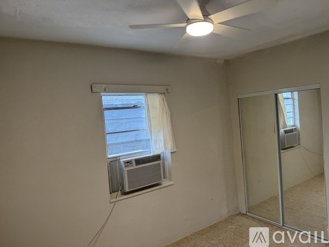 A room with a ceiling fan, a window with blinds, and a wall-mounted air conditioner unit.