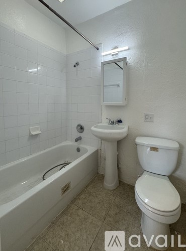 A white toilet sits next to a sink and bathtub in a bathroom.