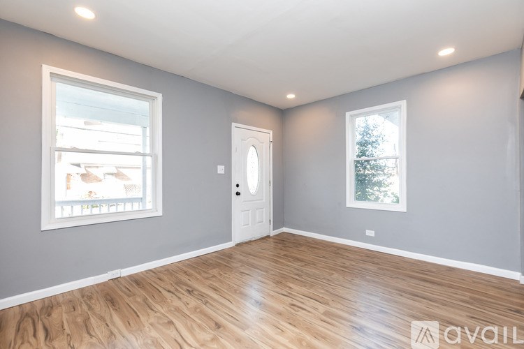 A room with wooden flooring and two windows.