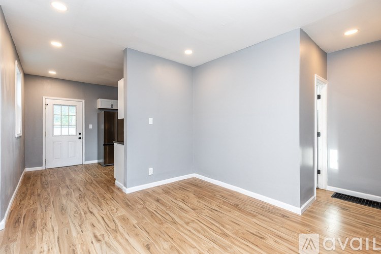 A spacious room with wooden flooring and white walls.