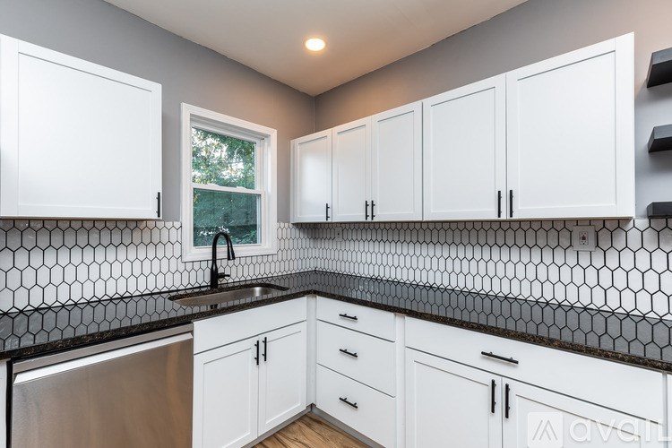 A kitchen with white cabinets and a black and white tiled backsplash.