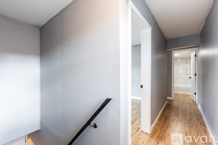 A hallway with a wooden floor and white walls.
