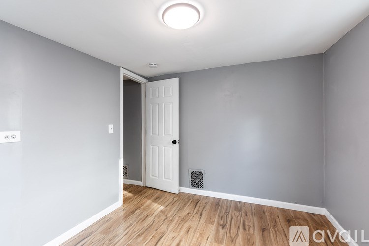 A room with a white door and a wooden floor.