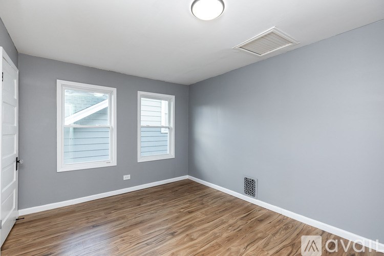 A room with wooden floors and two windows.