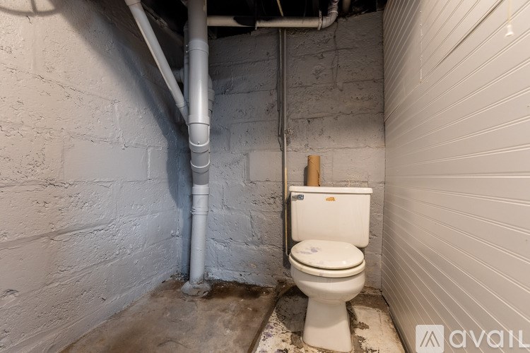 A dirty bathroom with a toilet and a pipe.