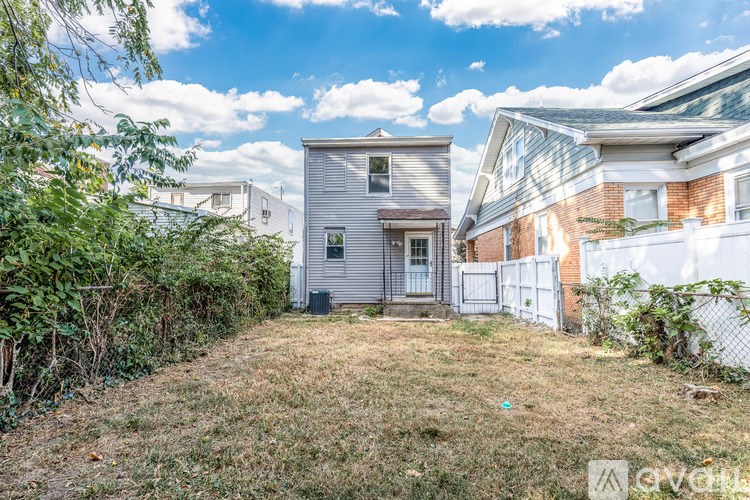 A backyard with a fence and a house in the background.
