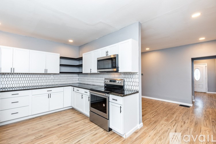 A kitchen with white cabinets and a black and white tiled backsplash.