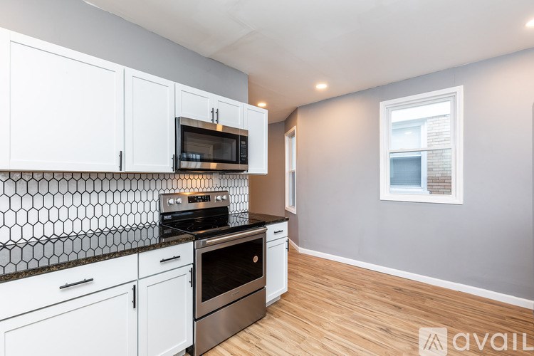 A kitchen with white cabinets and a black and white tiled backsplash.