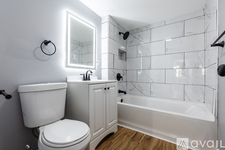 A white toilet sits next to a white bathtub in a bathroom with a mirror and a cabinet.