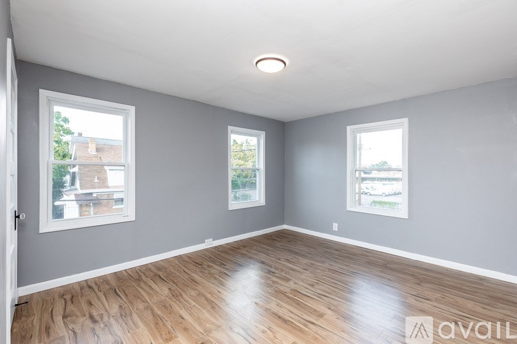A room with wooden floors and three windows.