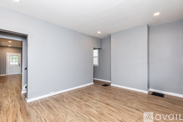 A spacious room with wooden flooring and white walls.