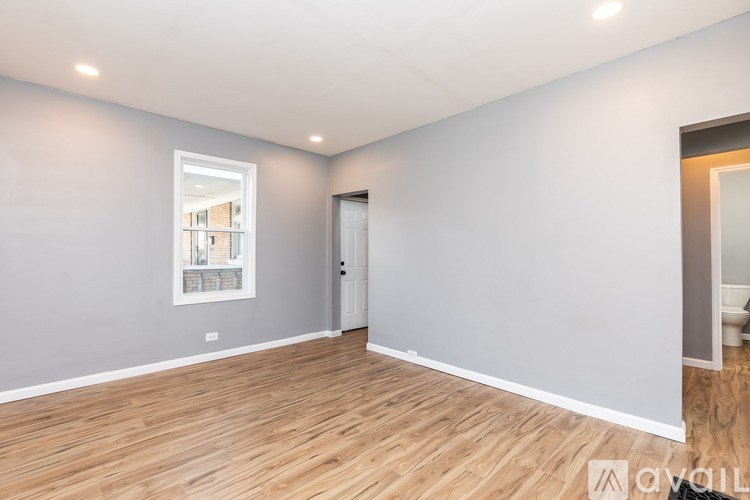 A spacious room with wooden flooring and a white door.