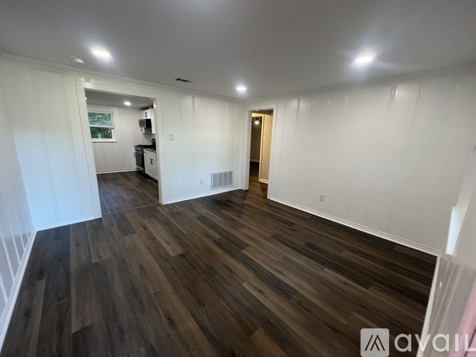 A room with wooden flooring and white walls.