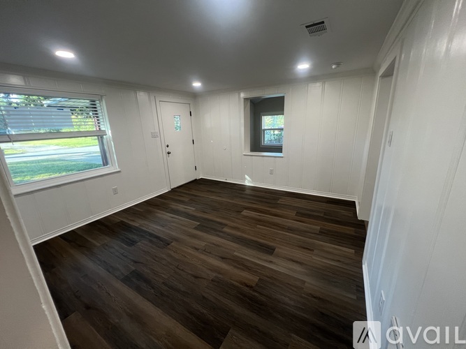 A room with wooden flooring and white walls.