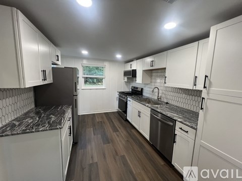 A kitchen with white cabinets and a marble countertop.