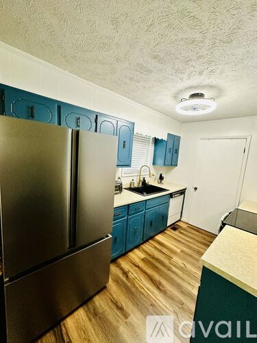 A kitchen with a stainless steel refrigerator and wooden floors.