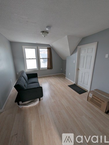 A living room with a black chair and a window.