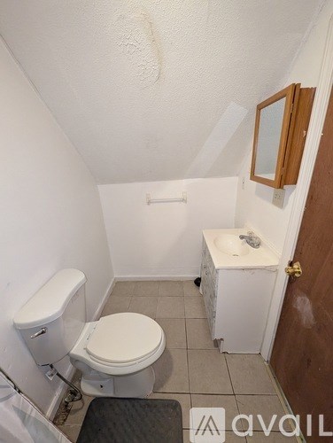 A small bathroom with a toilet, sink and mirror.